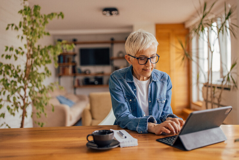 Mujer sentada frente al computador revisando información sobre la PGU
